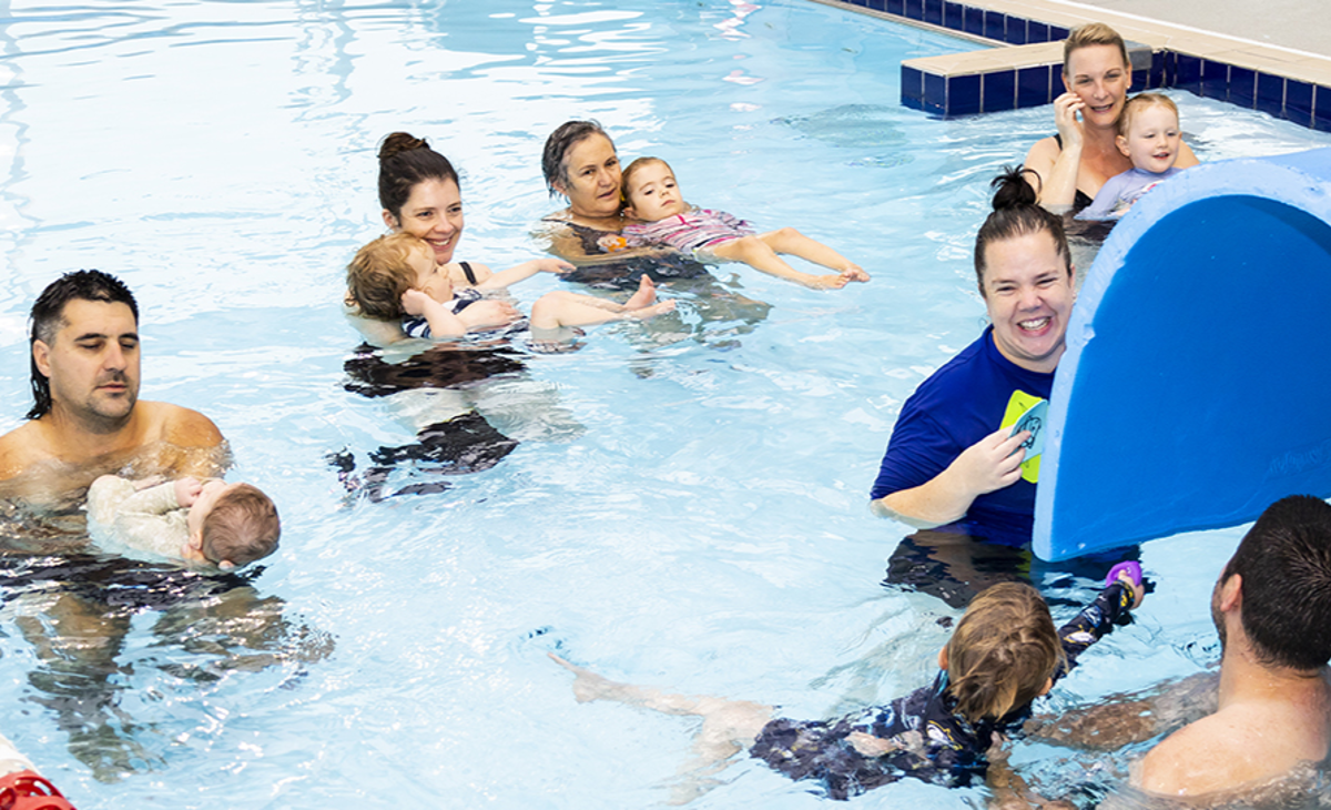Parents and caregivers with their babies and toddlers enjoying Pēpi Time at Ōtaki Pool. Our professional instructor has created a tunnel using a foam mat for the little ones to swim through with their helper..