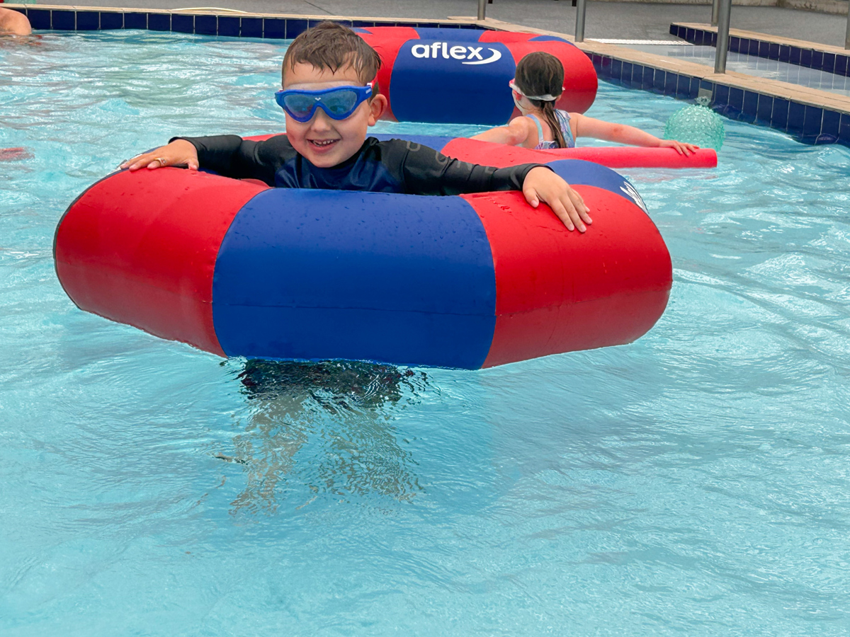 A young boy having splashing good time in an inflatable ring at Coastlands Aquatic Centre.